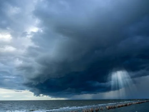 Sun beam in dark clouds and sky before thunderstorm at the seashore, Monsoon  Stock Photos