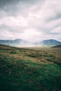 Sun beam through clouds on grass field Stock Photos