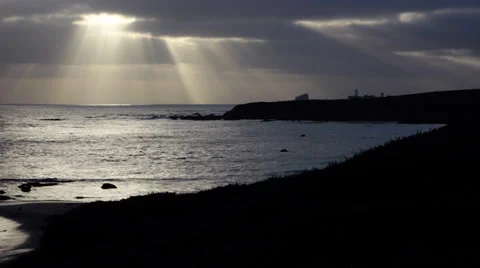 Sun beaming through clouds on waterfront with lighthouse Stock Footage 39219251