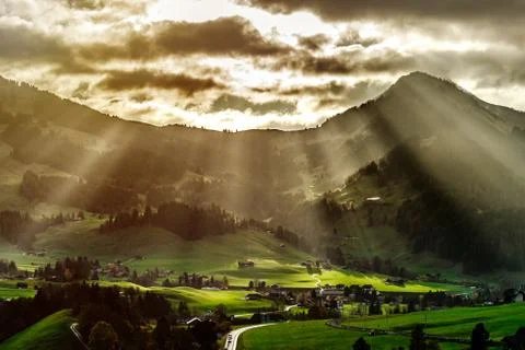 Sun beams lighting through the clouds and falling down to the little village Foto stock
