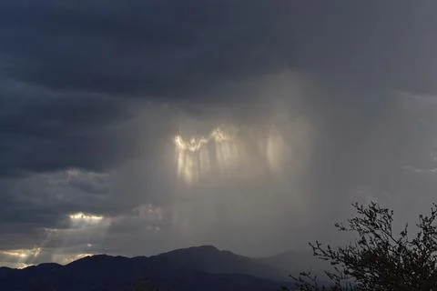 Sun beams pocking through a storm cloud over a mountain, Cottonwood, Arizona. Stock Photos