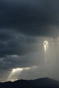 Sun beams pocking through a storm cloud over a mountain, Cottonwood, Arizona. Stock Photos