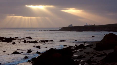 Sun beams through clouds on waterfront with lighthouse &amp; seals Stock Footage 39219265