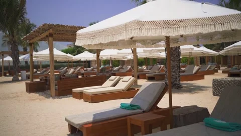 Sun beds, deck chairs and beach umbrellas on the sandy beach in Dubai in summer Video stock 246154959