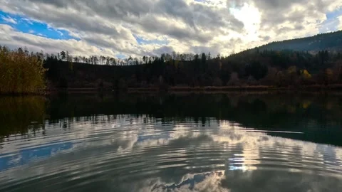 Sun behind clouds and hills reflected in the river Stock Footage 321283073