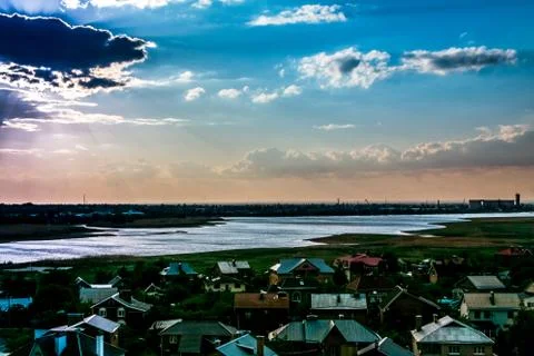 The sun behind the clouds on a blue sky over the Bay and the city rooftops Stock Photos