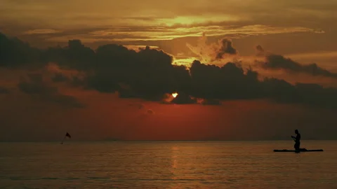 Sun behind the clouds during tropical sunset with silhouette on horizon Stock Footage 330874028