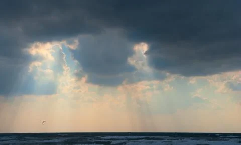 Sun behind dark storm clouds over the sea Stock Photos