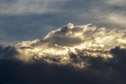 The sun behind dense cumulus clouds lights up their edge at the afternoon abo Stock Photos