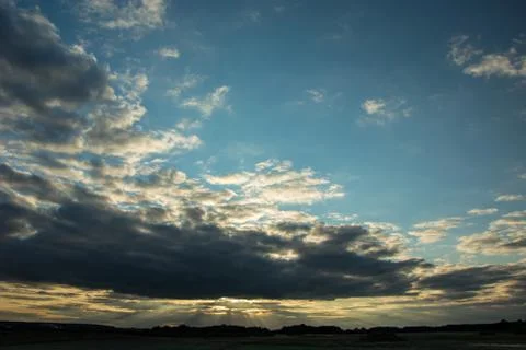 Sun behind gray clouds on sky, horizon and trees Stock Photos