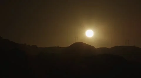 Sun behind hills and powerlines Stock Footage 44447406
