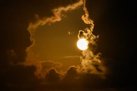 The sun behind a window of thick cumulus clouds Stock Photos