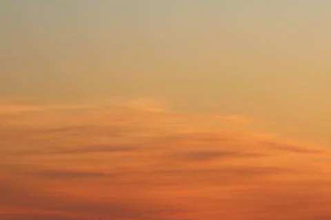 Sun below the horizon and clouds in the fiery dramatic orange sky at sunset or Stock Photos