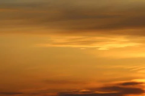Sun below the horizon and clouds in the fiery dramatic orange sky at sunset or Stock Photos