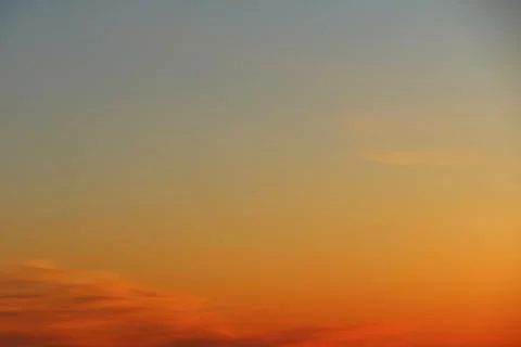Sun below the horizon and clouds in the fiery dramatic orange sky at sunset or Stock Photos