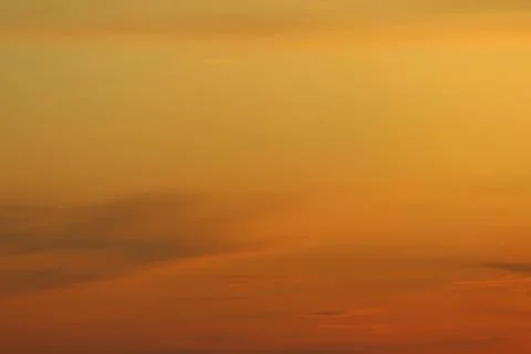 Sun below the horizon and clouds in the fiery dramatic orange sky at sunset or Stock Photos