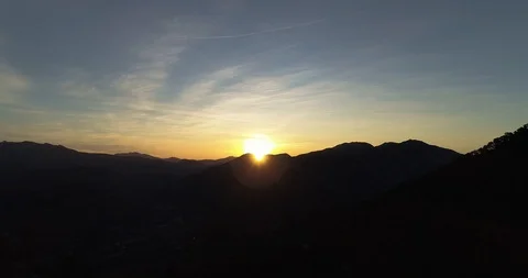 Sun blasts over mountain at sunrise with mountains silhouetted drone aerial 4k Stock Footage 125754305
