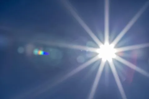 The sun in the blue sky with reflections in the camera lens Stock Photos