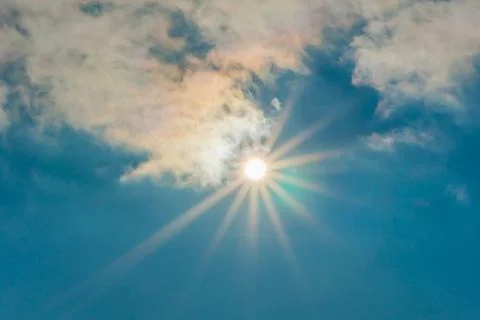 The sun in the blue sky under the clouds. Sunny day. Blue sky. Bright midday  Stock Photos
