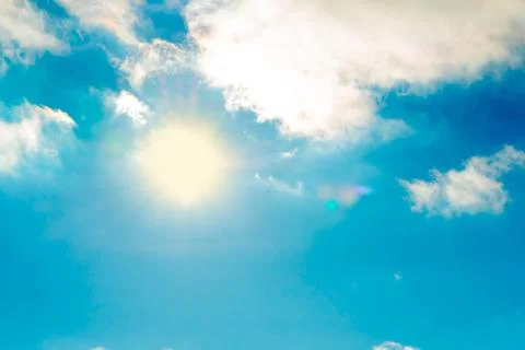 The sun in the blue sky under the clouds. Sunny day. Blue sky. Bright midday  스톡 사진