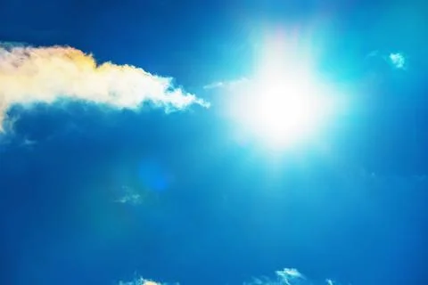 The sun in the blue sky under the clouds. Sunny day. Blue sky. Bright midday  Stock Photos