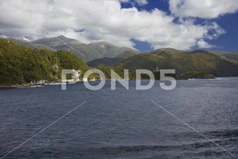 Sun breakes through the clouds at Dusky Sound. Stock Photos