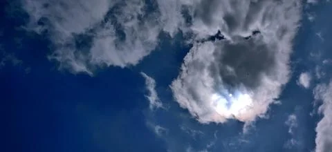 Sun breaking out from behind winter clouds in blue sky Foto stock