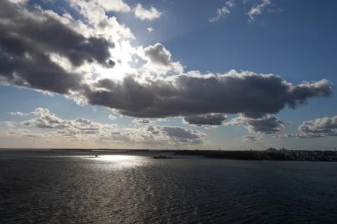 Sun breaking through clouds over water Stock Photos