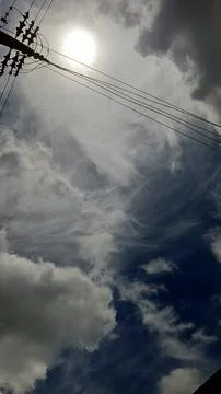 Sun Breaking Through Dramatic Clouds with Power Lines 스톡 사진