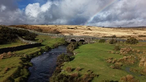Sun breaking through the  rain clouds and rainbow on Dartmoor Stock Footage 327972632