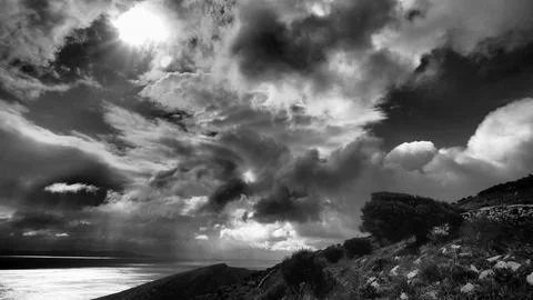 Sun breaking through storm clouds over Kea Island - dramatic black and white Stock-Fotos