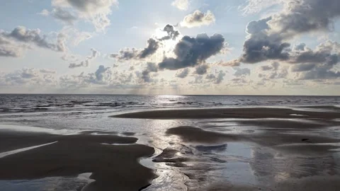 Sun breaks through clouds over calm ocean waves Stock Footage 332599209
