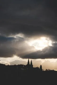 Sun breaks through the clouds at sunset and sends its rays towards buildings  Foto stock