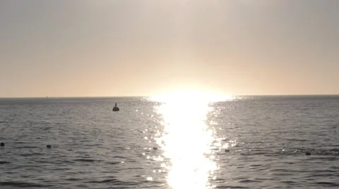 Sun burns the open ocean as the moored yacht bobs in the calm sea Stock Footage 67970893