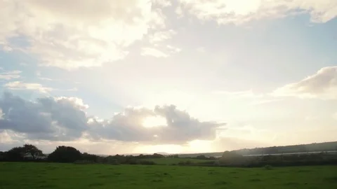 Sun Bursting through clouds over field Stock Footage 73559264