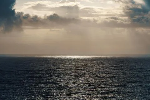 The sun is casting its rays through the clouds onto the ocean Stock Photos