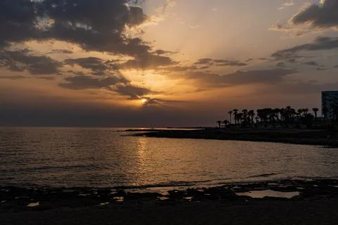 The sun casting rays of orange light over the coast line of Paphos on the i.. Stock Photos