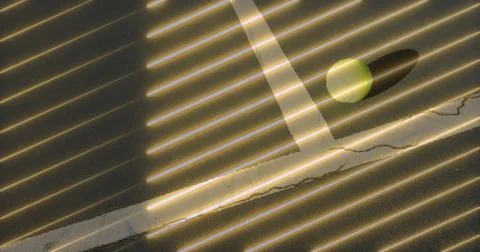 Sun casting stripes across cracked paint tabletop in room with yellow-green ball Foto stock