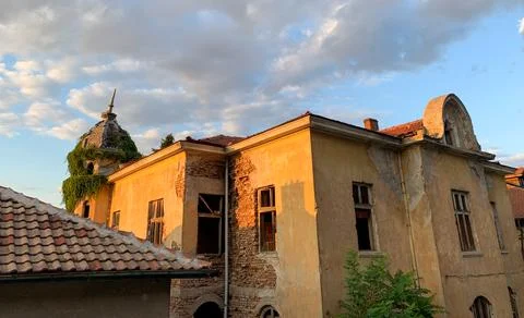 The sun casts a warm glow on an old, weathered mansion Stock Photos