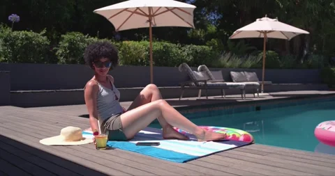 Sun is causing woman to tilt face up while sipping cold drink for sunbathing by Stock Footage 340987472
