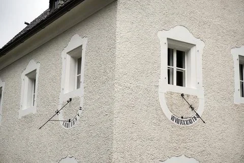 Sun clock or watch on white corner of house. old-fashioned time checking by s Stock Photos