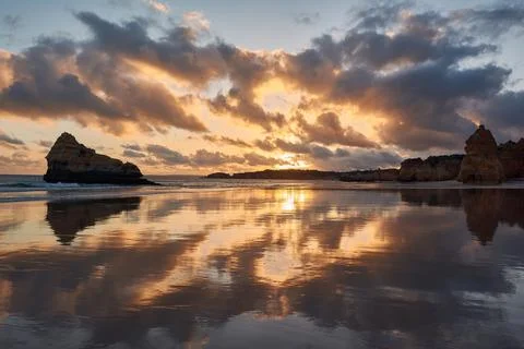 Sun, clouds and limestone rock formations reflecting in the  mirror-like surf Stock Photos