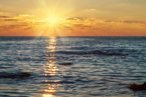 Sun in the clouds at sunset over the sea Stock Photos