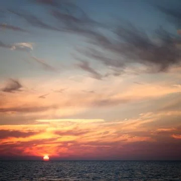 Sun in the clouds at sunset over the sea Stock Photos