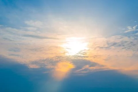 Sun in the clouds at sunset. The sunbeam illuminates the sky in orange 写真素材