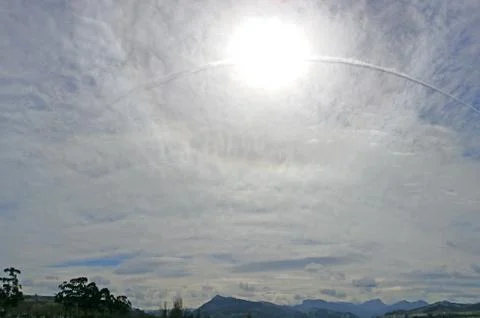 Sun on the cloudy sky with inverse track from airplane. Stock Photos