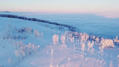 Sun coming up from behind the snow-covered mountains illuminates the sea of clou Stock Footage 227189008