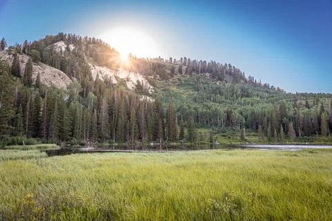 Sun Coming Up Over a Mountain in the Background With a Lake in the Foreground Foto stock