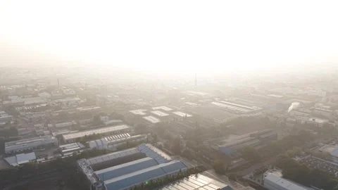 The sun creates backlight effect, casting long shadows across factory roofs and Stock Footage 331561546