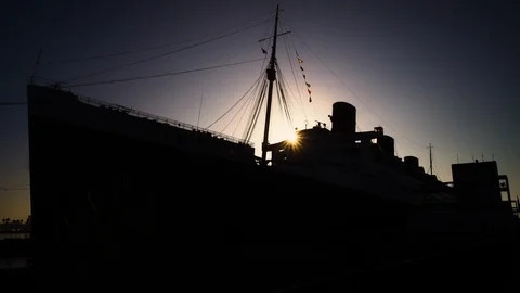 Sun crests over the silhouetted hull of the 1930s Ocean Liner the Queen Mary 스톡 동영상 116513046